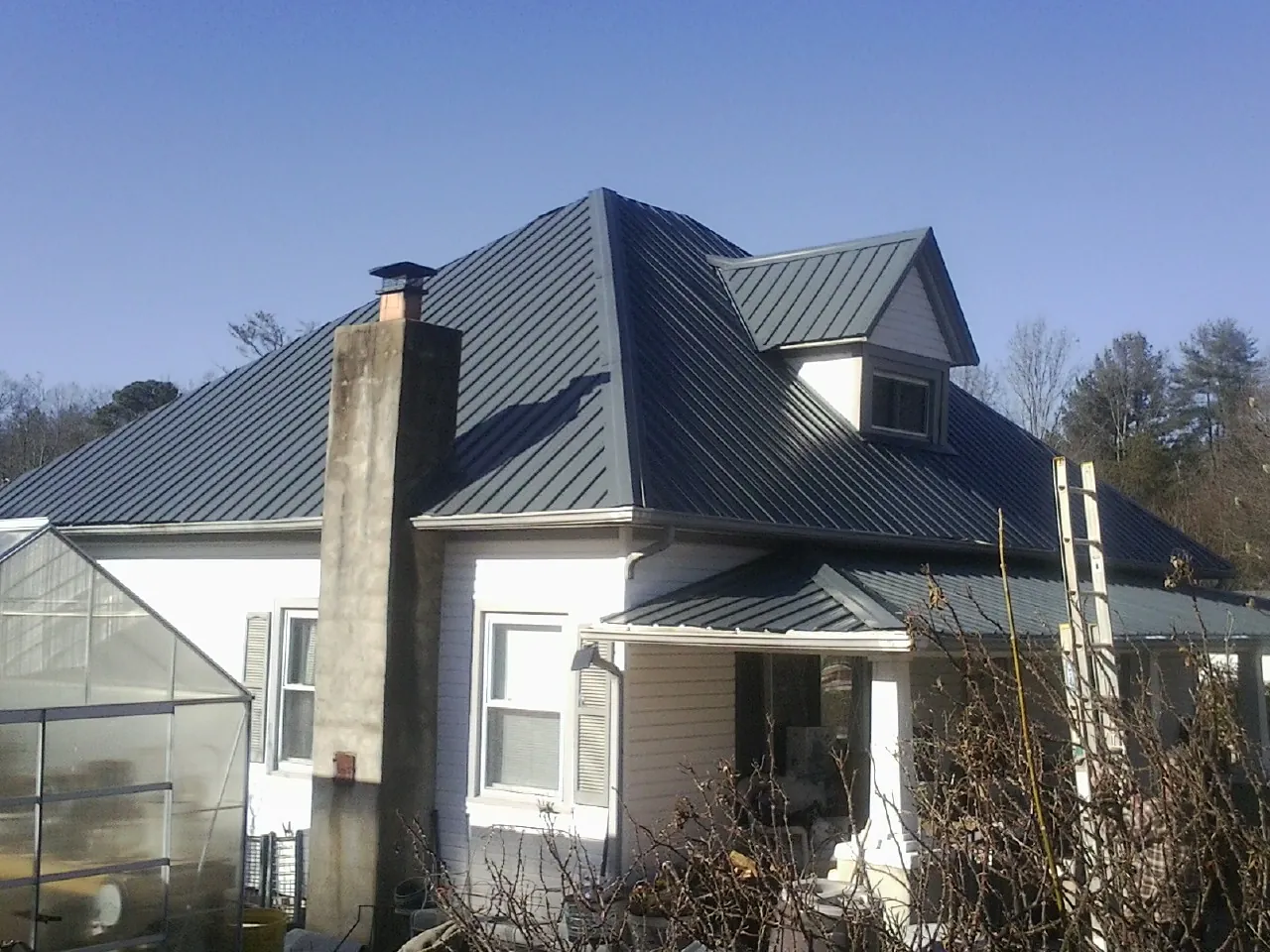 Dark blue standing seam metal roof on a white farmhouse with dormer — Slate & Tile Roof Repair by Roofing Brothers in Courtenay
