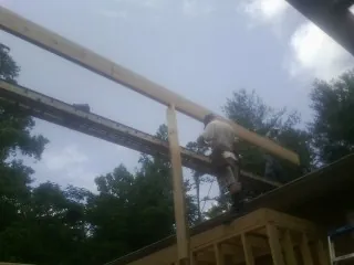 Carpenter setting a ridge beam over a new addition frame — Ice Dam Removal by Roofing Brothers in Courtenay