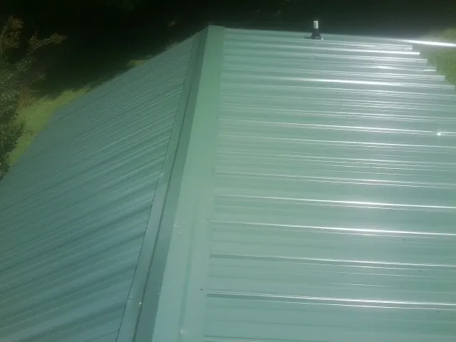 New green metal panels meeting at the ridge of a roof — Flat Roof Repair work by our crew in Courtenay