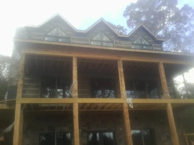 Dormers and porch framing on a large log home under construction — Roof Coating work by our crew in Courtenay