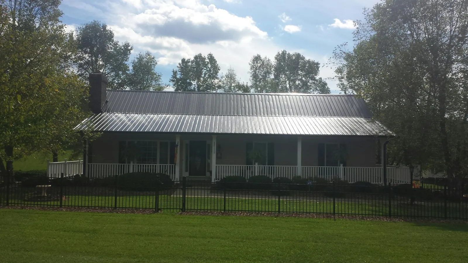 Gray metal roof on a brick ranch with a full width front porch — Gutter Guard Installation work by our crew in Courtenay