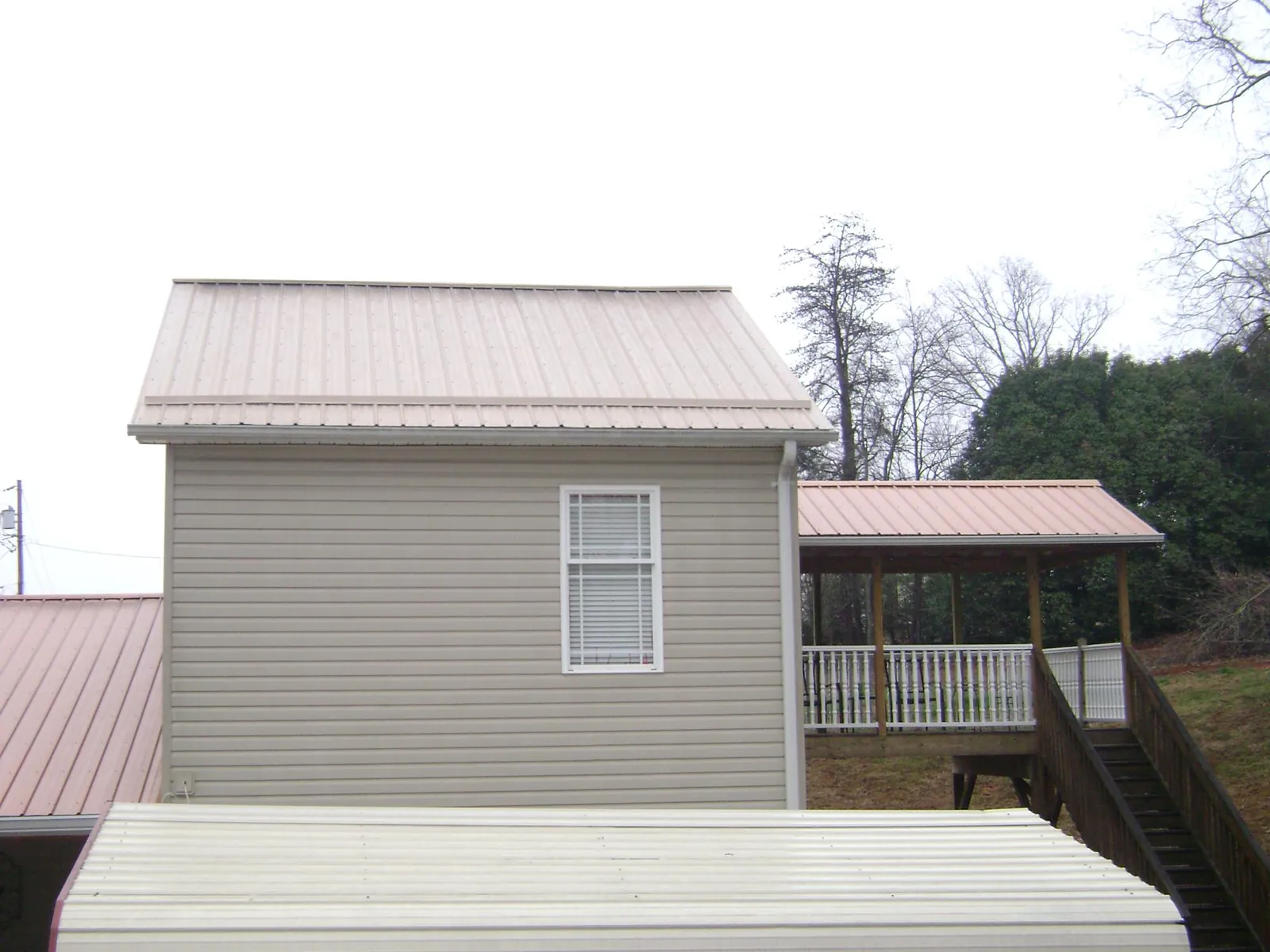 Tan metal roofs on a two story addition and attached porch, from a Roof Replacement job in Courtenay