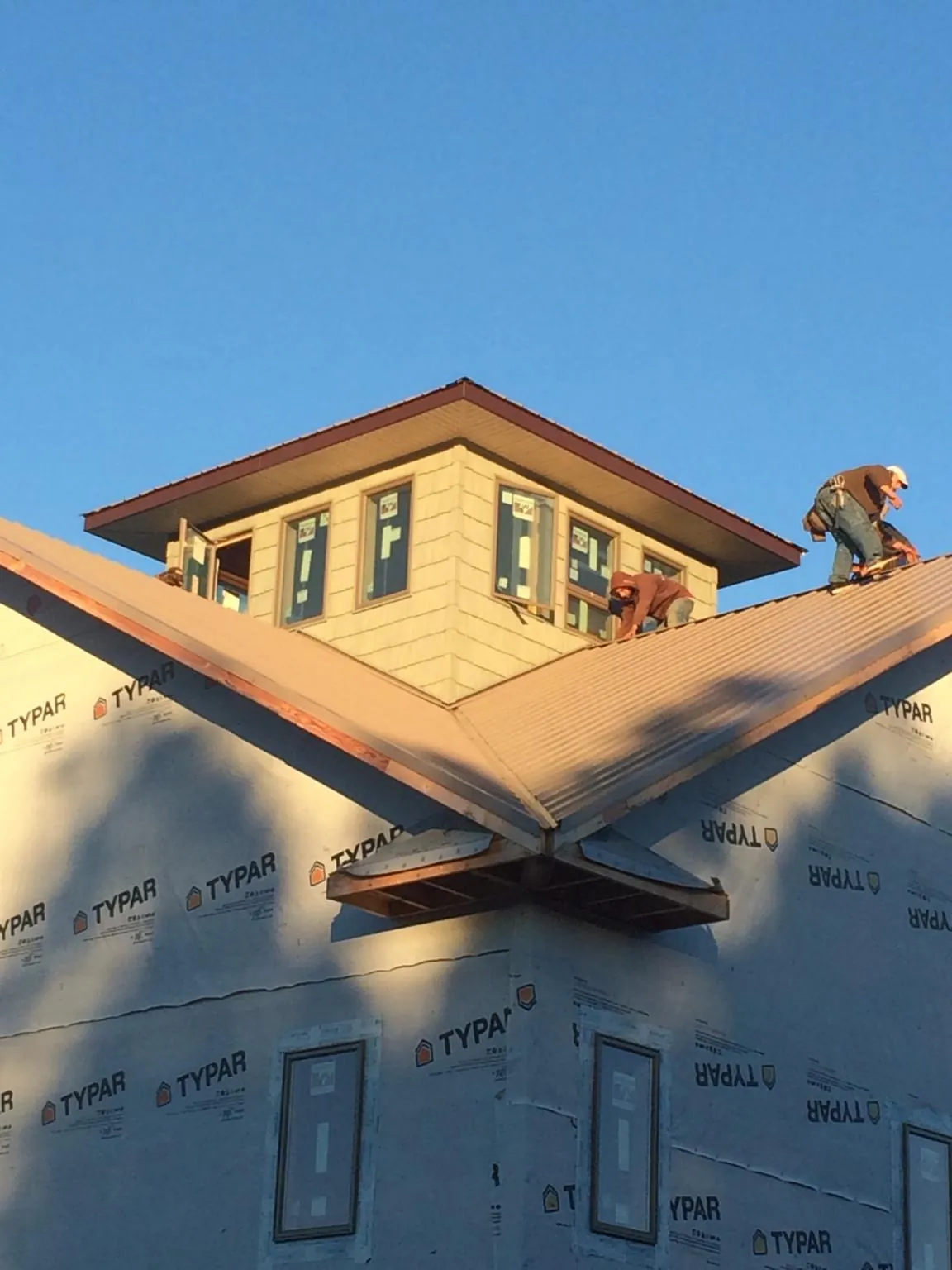 Roofers working around a rooftop cupola on a new metal roof at sunset — Roof Waterproofing in Courtenay by Roofing Brothers